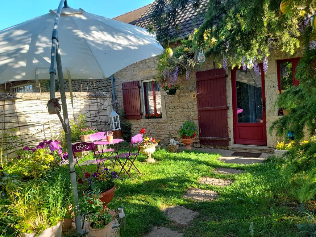 una casa con una mesa y una sombrilla en el patio en Aux Glycines, en Marcilly-Ogny