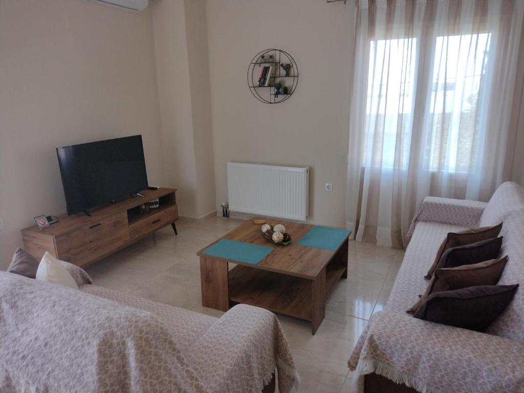 "Thea" Valis Apartments في Melissátika: غرفة معيشة مع تلفزيون وطاولة قهوة خشبية