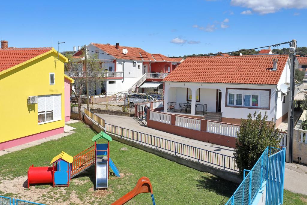 einen Hof mit einem Spielplatz und einem Haus in der Unterkunft Apartments Ivana Bibinje in Bibinje