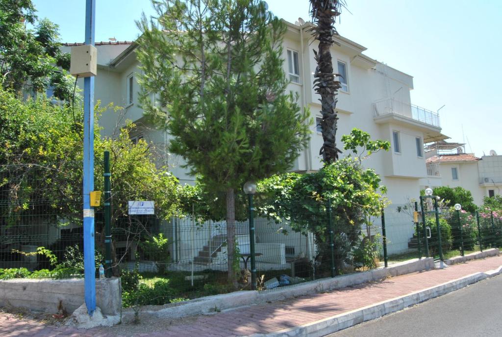 a white building with trees in front of a fence at MARTILI VİLLA LARA ANTALYA in Antalya
