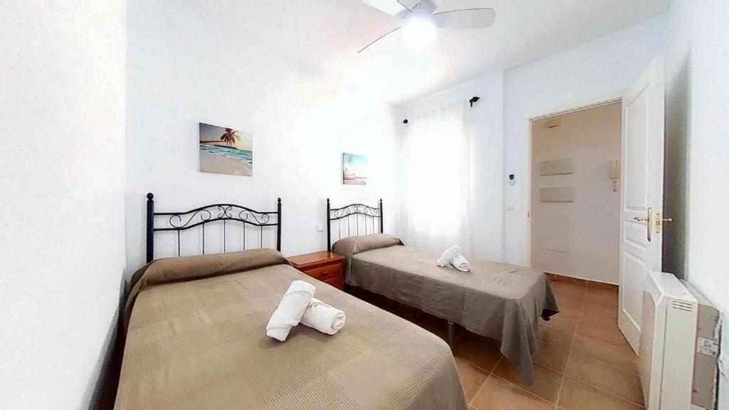 sypialnia z dwoma łóżkami i oknem w obiekcie Coqueto y práctico apartamento en pueblo de Zahara w mieście Zahara de los Atunes