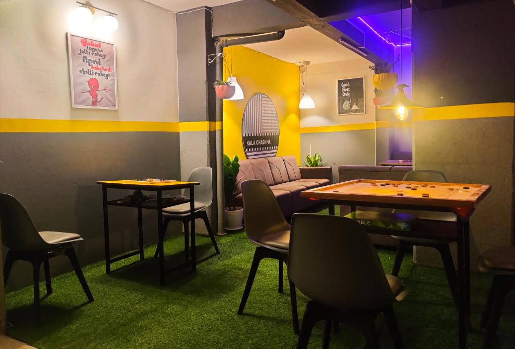 una stanza con due tavoli e sedie e un divano di Procida Hostel by Vibe Village a Pune