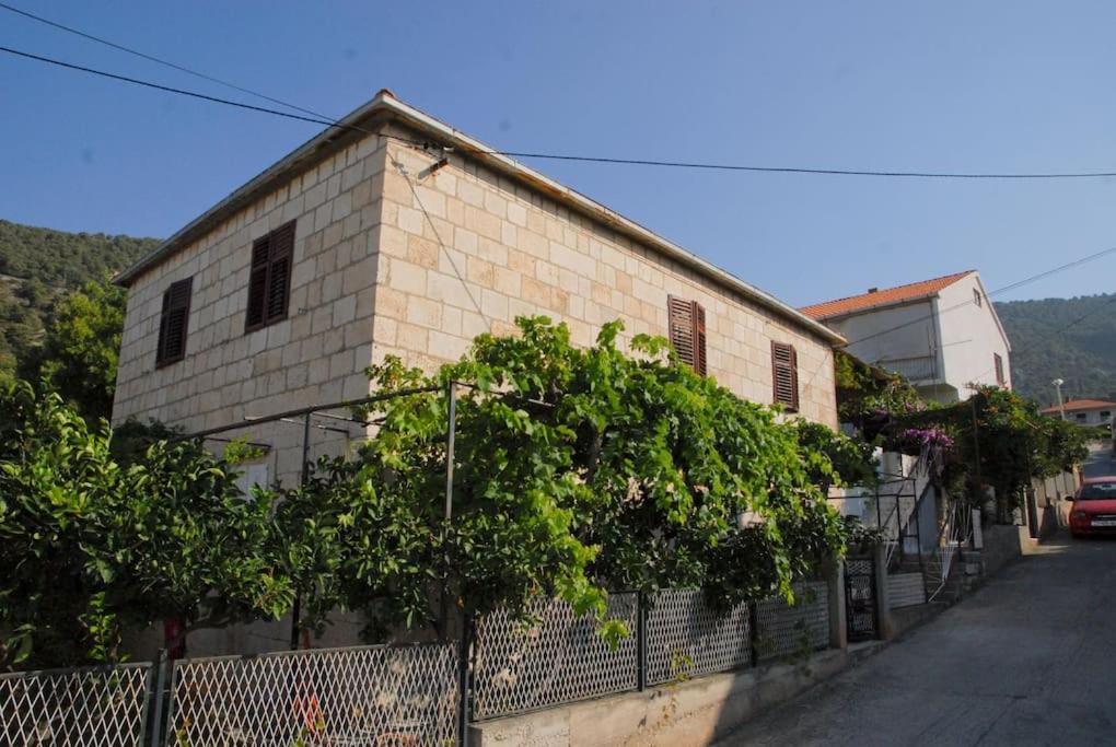 a brick building with a fence next to a street at Apartment Goli in Komiža