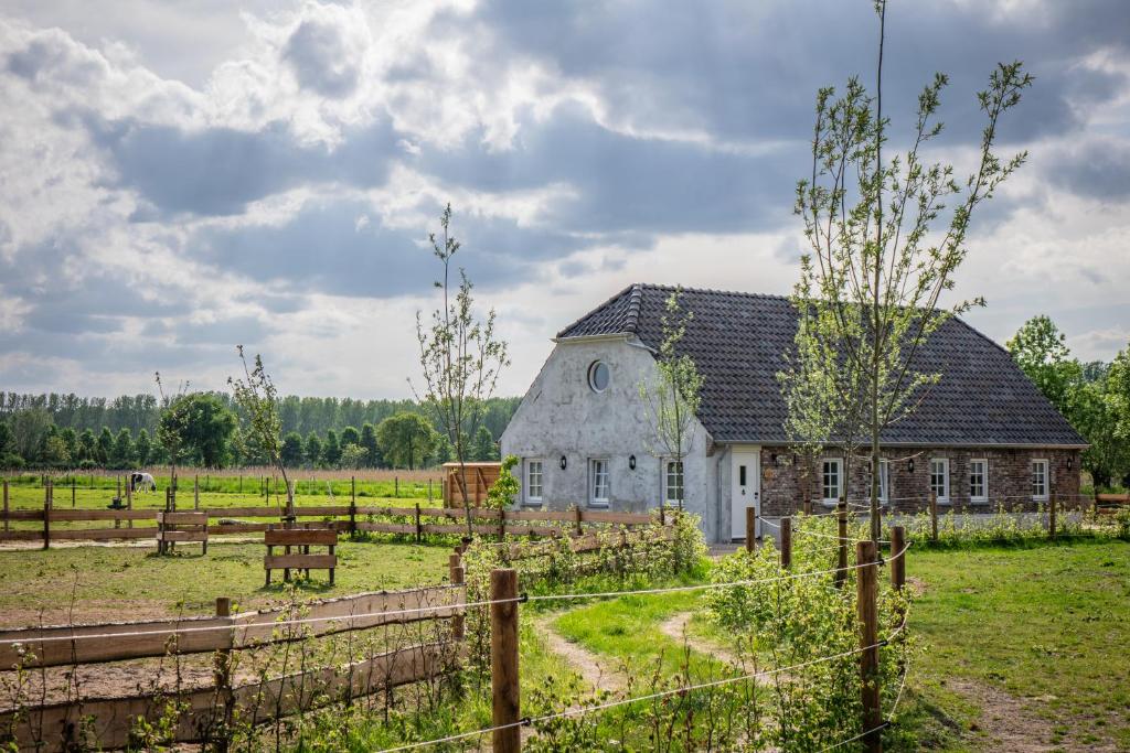 un antiguo granero en un campo con una valla en B&B Hoeve Klein Haneveld, en Sint-Oedenrode