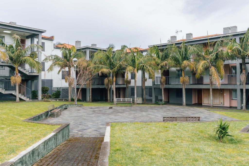 un patio con palmeras frente a un edificio en Quintas do Mar, en Ribeira Grande