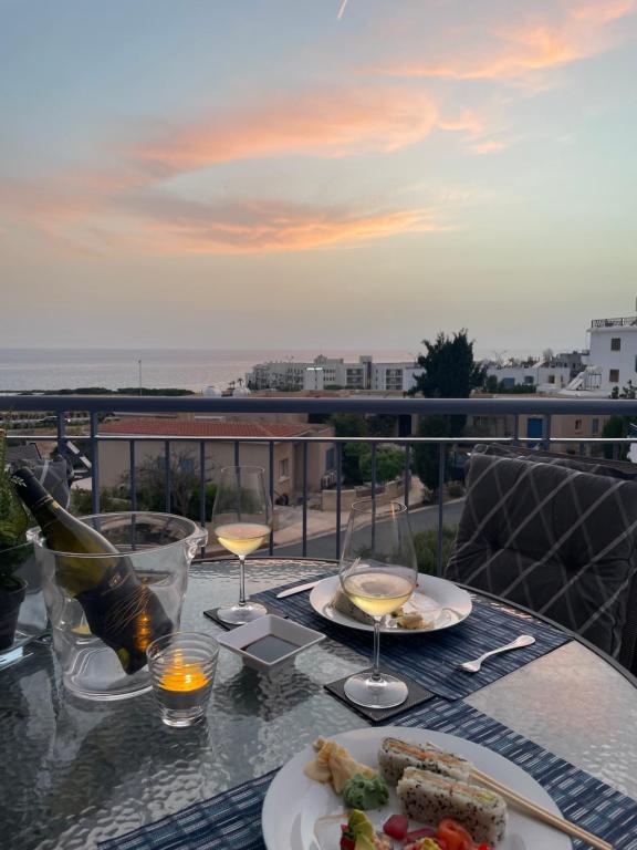 a table with two plates of food and wine glasses at Direct Sea View & Quality Bed - Kings Palace 1 bed in Paphos City