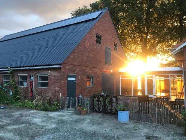una casa de ladrillo rojo con el sol brillando en ella en Bed and Breakfast ChickpointCharlie en Haaksbergen