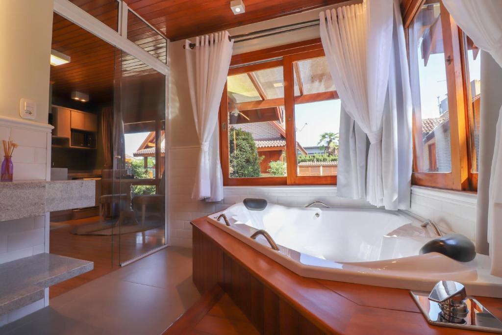 baño con bañera y ventana grande en Cabanas Belo Destino, en Gramado