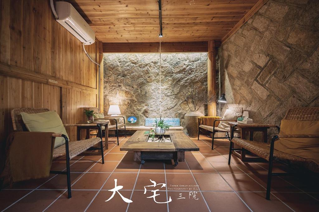 Cette chambre est dotée d'une table, de chaises et d'un mur en pierre. dans l'établissement 大宅三院青年旅舍 背包客棧, à Beigan