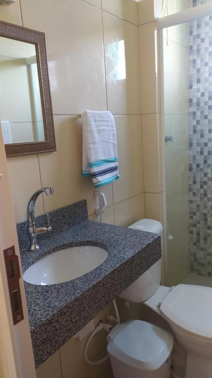 a bathroom with a sink and a toilet and a mirror at Suíte Porto das Dunas in Salvador