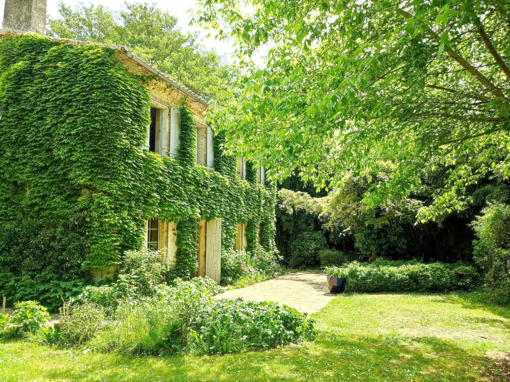 une maison recouverte de lierre avec une passerelle dans une cour dans l'établissement Chambre d'hôtes Le Moulin de Moulis, à Moulis-en-Médoc