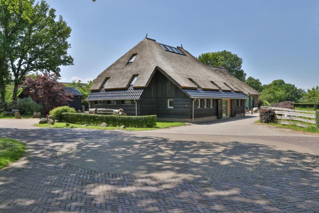 Ansen的住宿－erve Middendorp，一座带茅草屋顶的建筑,前面有一条鹅卵石街道