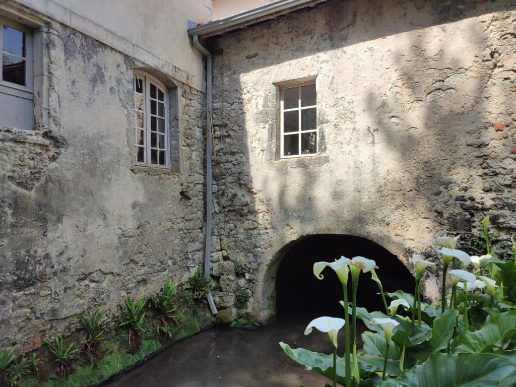 a stone building with a door and flowers in front of it at Chambre d&#39;hôtes Le Moulin de Moulis in Moulis-en-Médoc