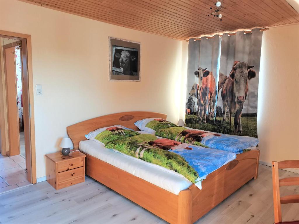 1 cama en un dormitorio con una pintura de una vaca en Biene's Bärenstube en Elze