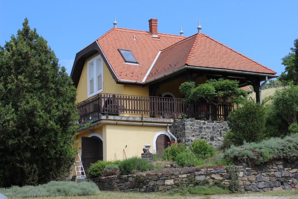 a house with a balcony and a roof at Napsugár Vendégház in Badacsonytördemic