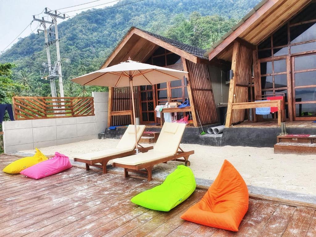 un groupe de chaises et un parasol sur une terrasse dans l'établissement Teras Pahawang, à Sukojayo