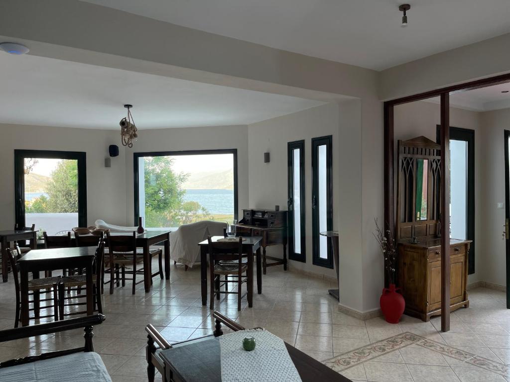 a living room with tables and chairs and windows at Nisea Hotel Samos in Pythagoreio