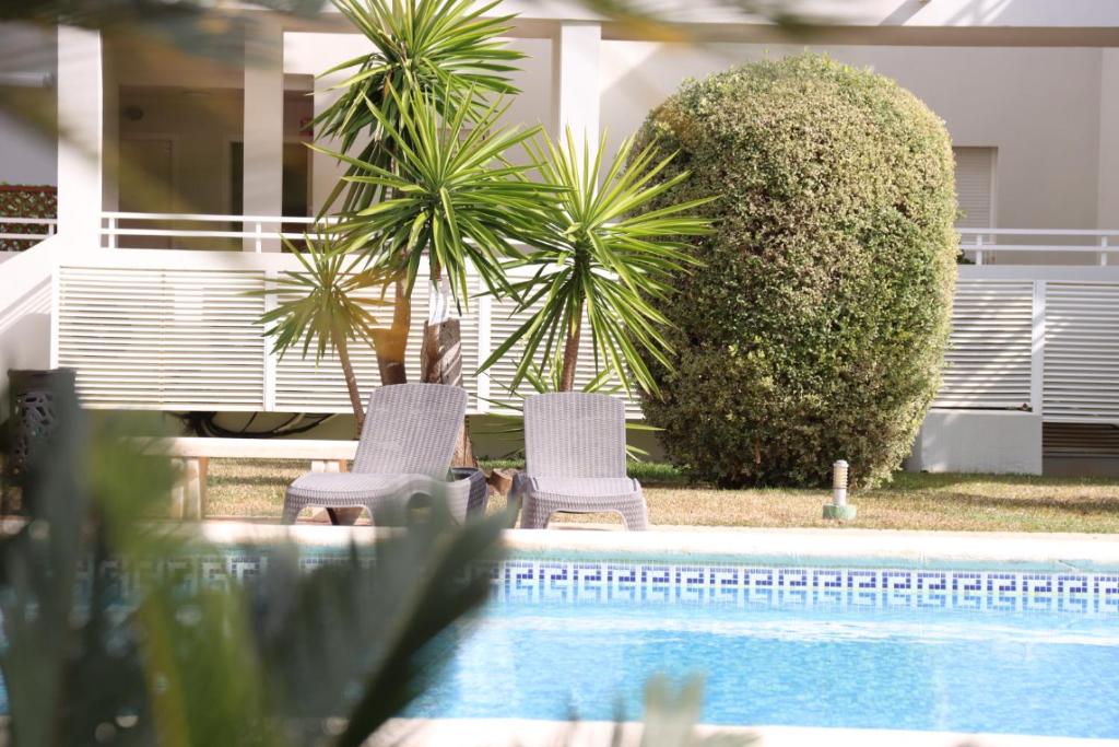 2 Stühle und ein Pool mit zwei Palmen in der Unterkunft Blue Oliva Nova MET & Golf in Oliva