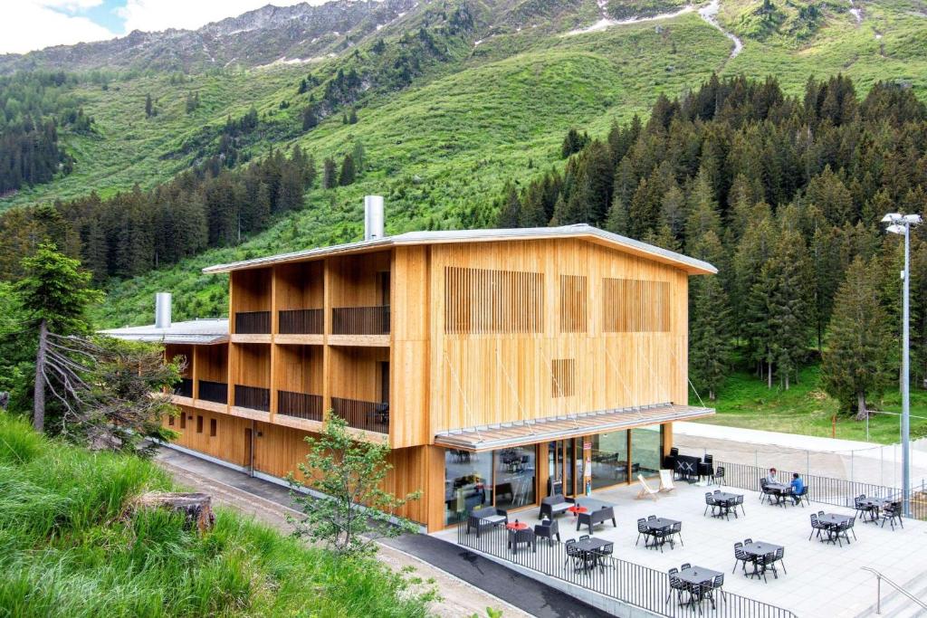 a building with tables and chairs in front of a mountain at Campra Alpine Lodge & Spa in Olivone