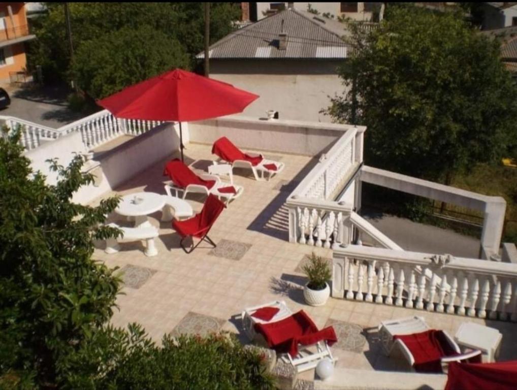 een patio met een tafel en stoelen en een rode parasol bij Happiness in Senj