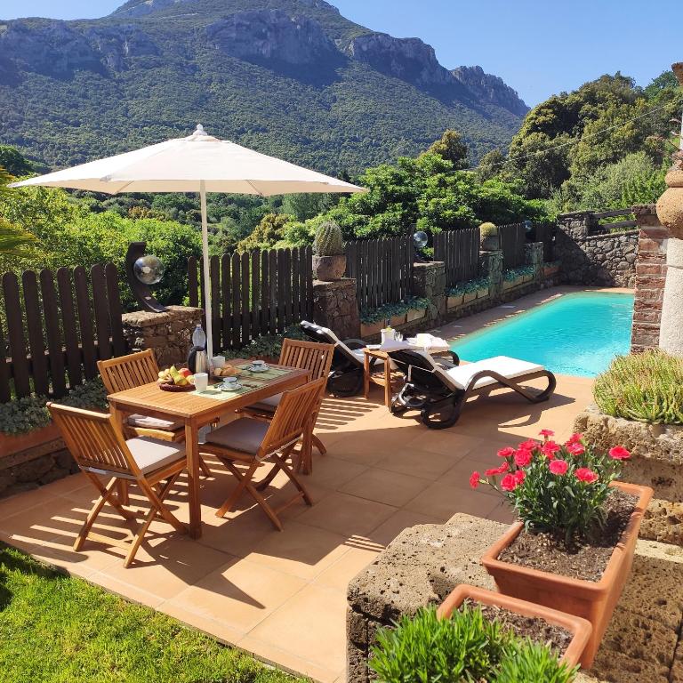 a patio with a table and an umbrella and a scooter at Casa Bados in Dorgali