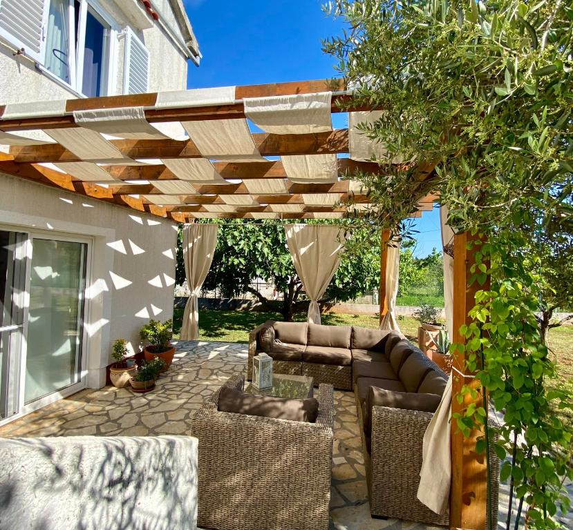 patio z drewnianą pergolą i krzesłami w obiekcie Beautiful island house Ugljan w mieście Ugljan