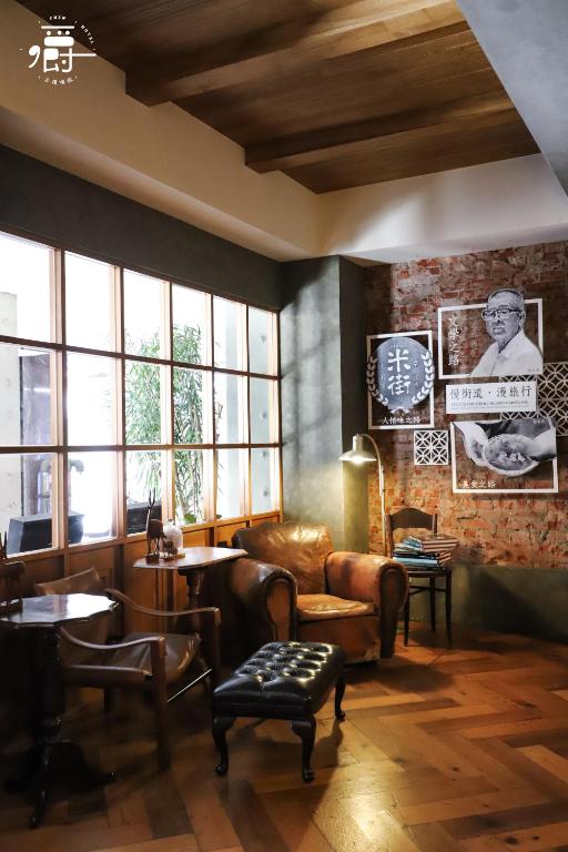 Una sala de estar con un sofá, mesas y ventanas. en Roots Chew Hotel, en Tainan