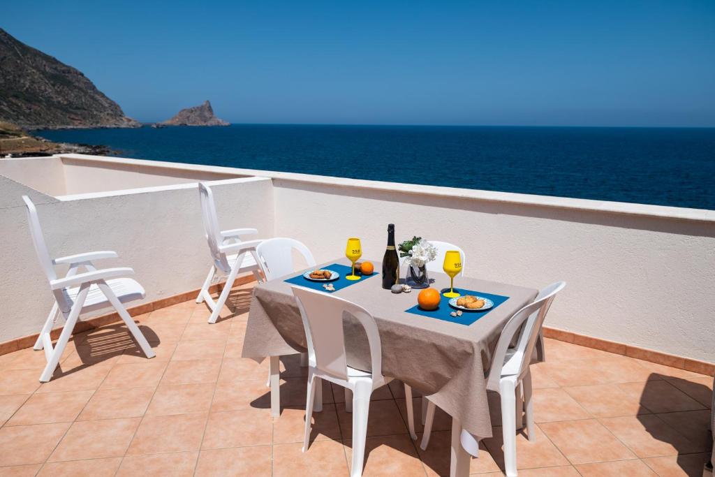 un tavolo e sedie su un balcone con vista sull'oceano di La terrazza del sole “ apartments “ a Marettimo