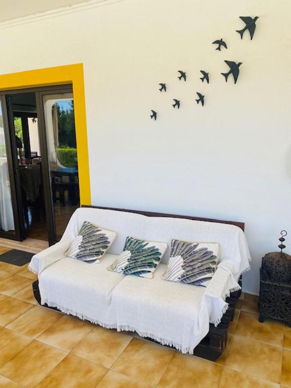 a living room with a white couch with black birds on the wall at Quinta das Andorinhas in Carvoeiro