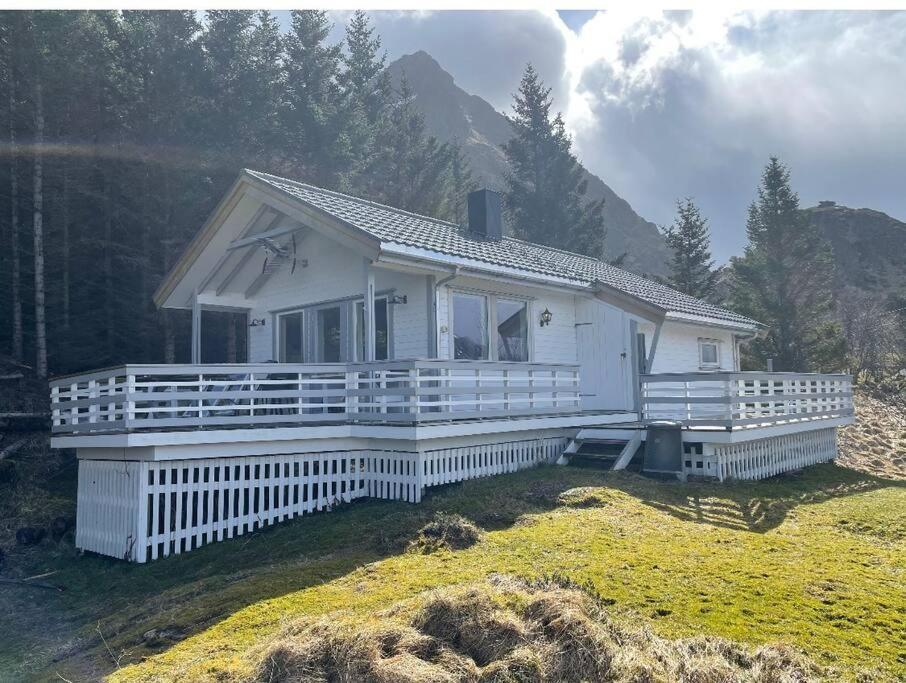 a small white house with a large porch at Vettinghytta, close to the sea with amazing view. in Gravdal