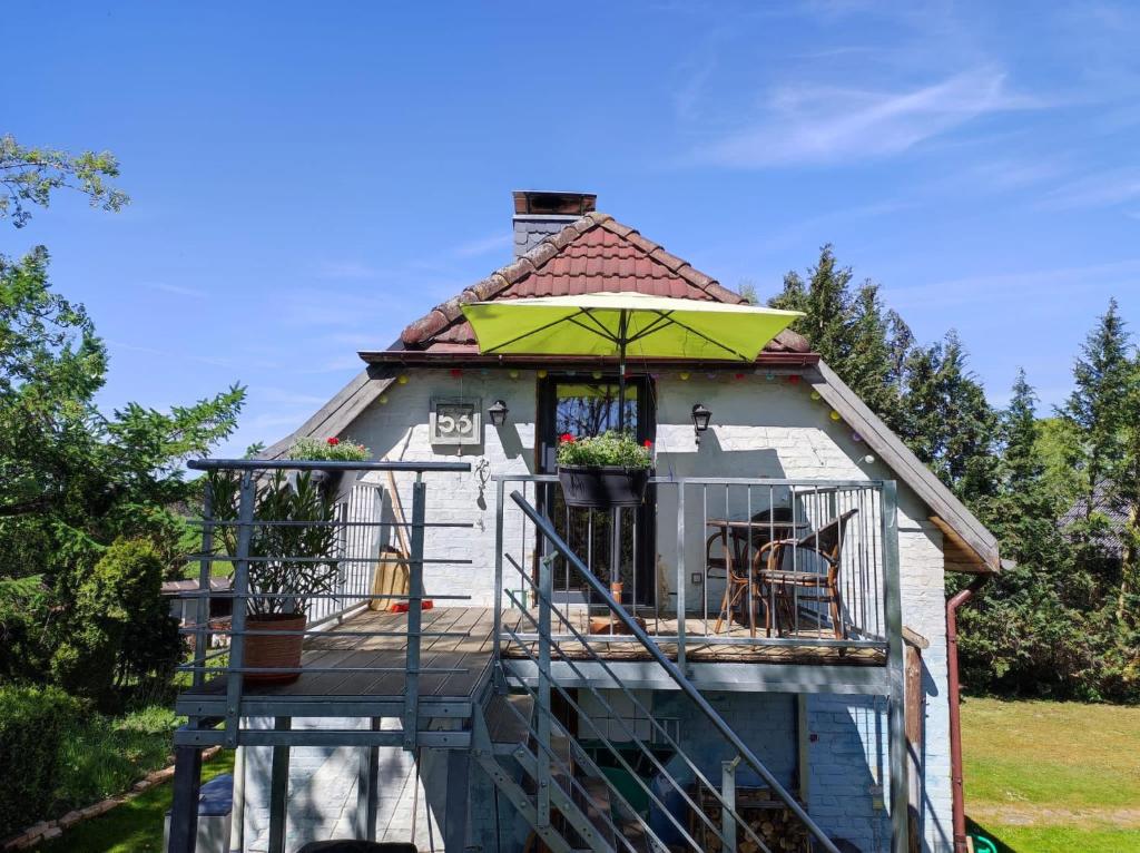 uma casa com uma varanda com um guarda-chuva verde em Baldies Tenne in Ostseenähe em Wendorf