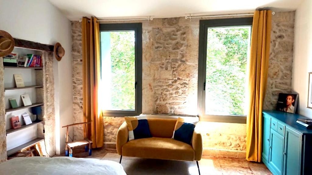 1 dormitorio con silla y 2 ventanas en Grande suite sur jardin dans Montpellier centre, en Montpellier