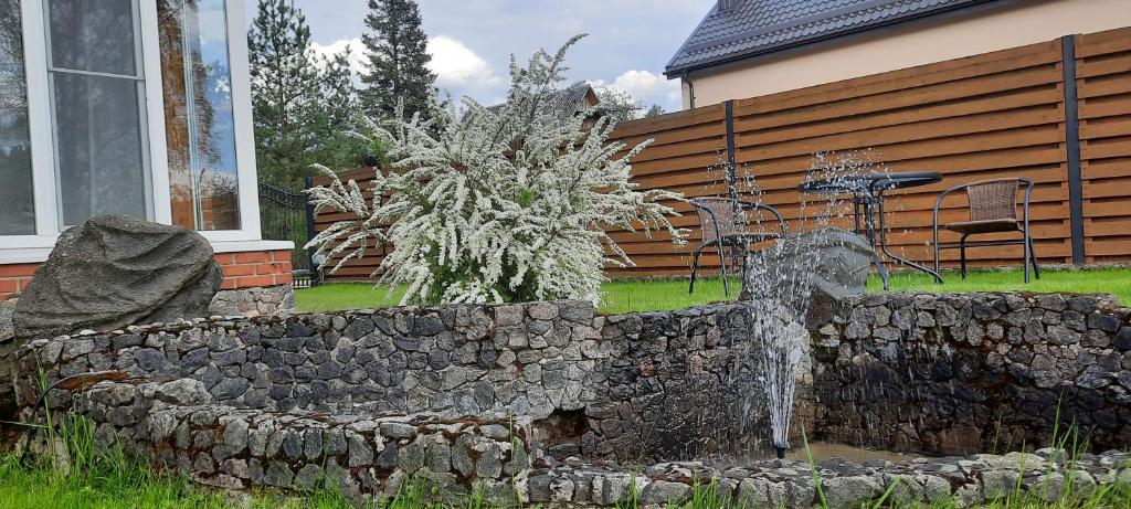 a stone retaining wall with a fountain in front of a house at Verkių Namelis in Vilnius