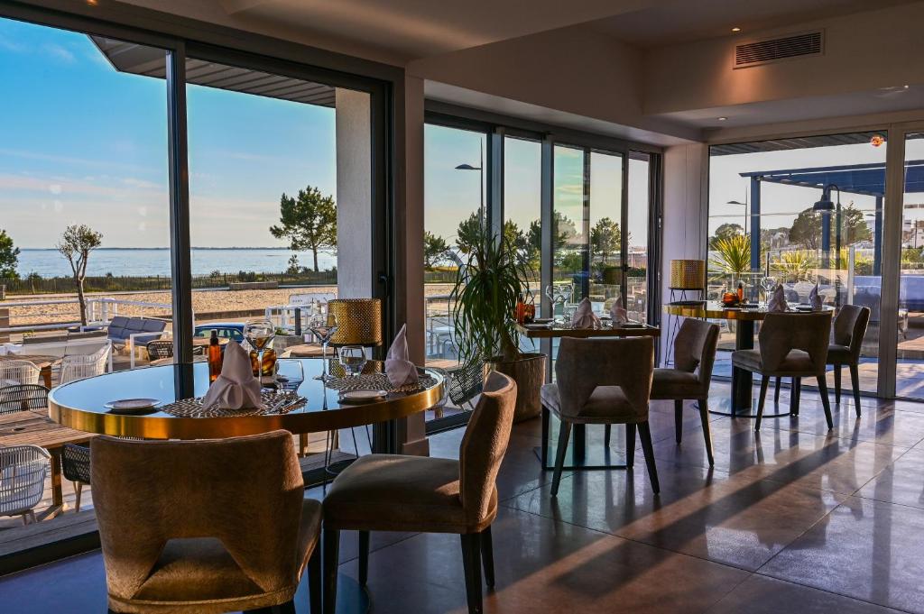 - un restaurant avec des tables et des chaises et une vue sur l'océan dans l'établissement Le Diana Hôtel & Spa NUXE, à Carnac