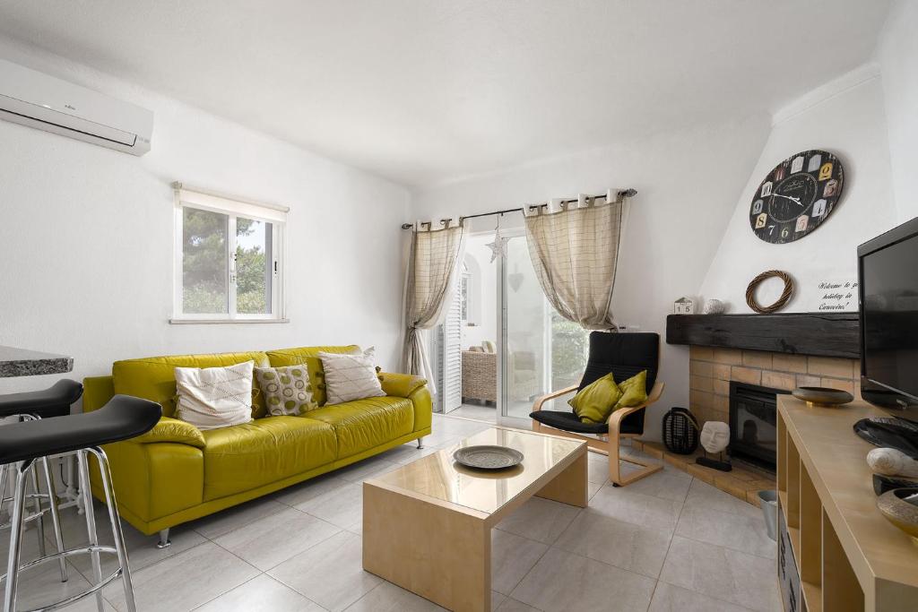 a living room with a yellow couch and a fireplace at Casa Maresia - Apartamento 2 quartos e piscina - Praia Carvoeiro in Carvoeiro