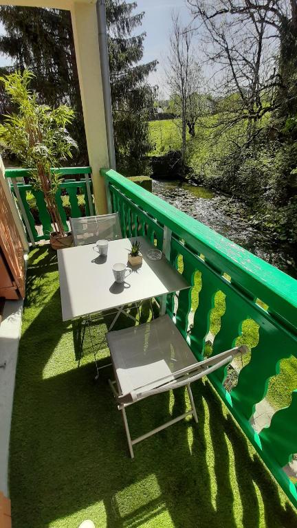 einen weißen Tisch und Stühle auf einem Balkon mit Flussblick in der Unterkunft Escapade Au Calme De La Rivière in Métabief