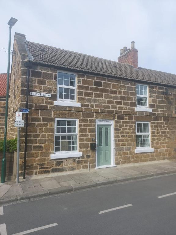 a brick building with a green door on a street at Poets Cottage in Skinningrove