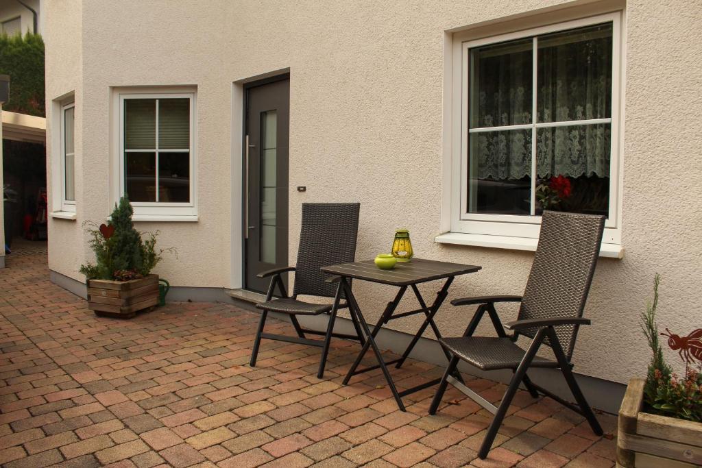un patio con 2 sillas y una mesa frente a un edificio en Ferienwohnung Waldblick, en Brilon