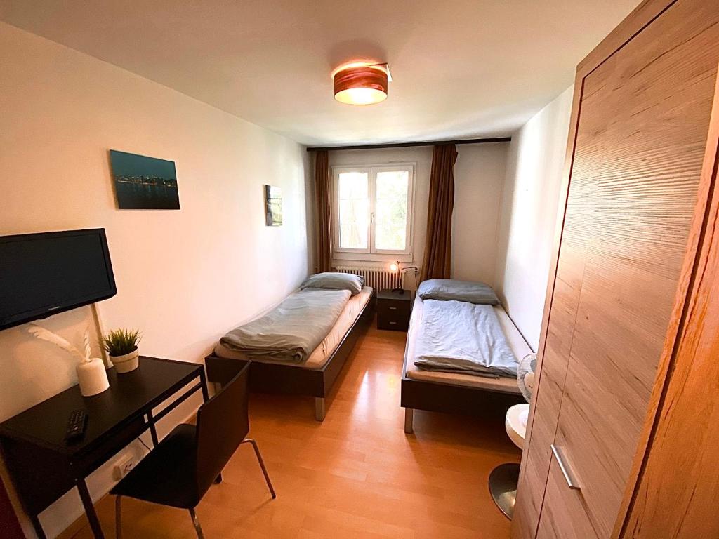 Habitación con 2 camas, escritorio y ventana. en Budgetapartment Konzil von Swisspartments en Arbon