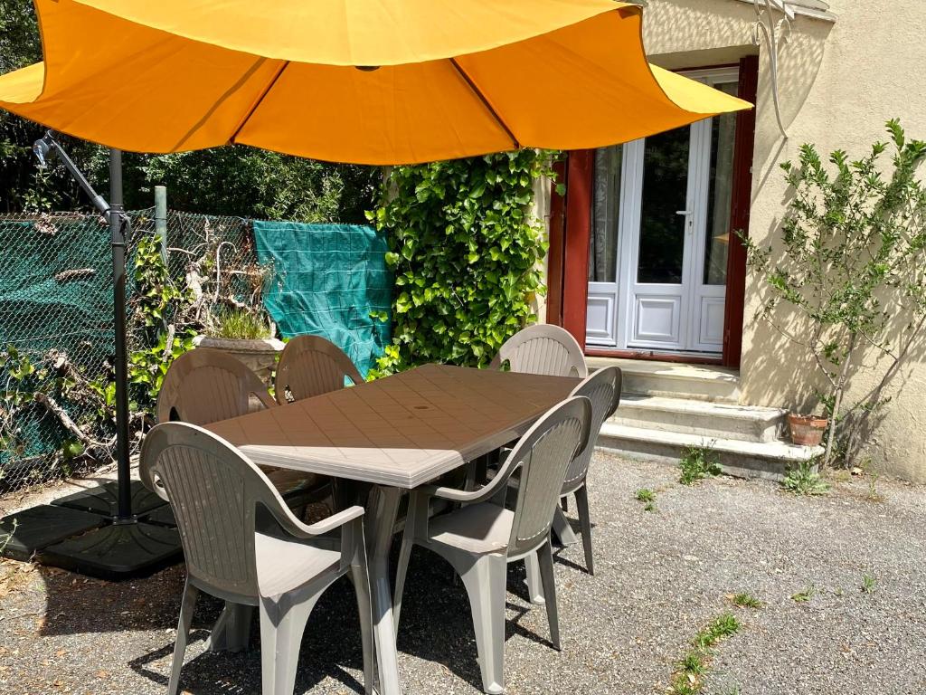 una mesa de madera con sillas y una sombrilla en Appartement F3 de 60 m² au rez de chaussée d'une villa, en Vézénobres