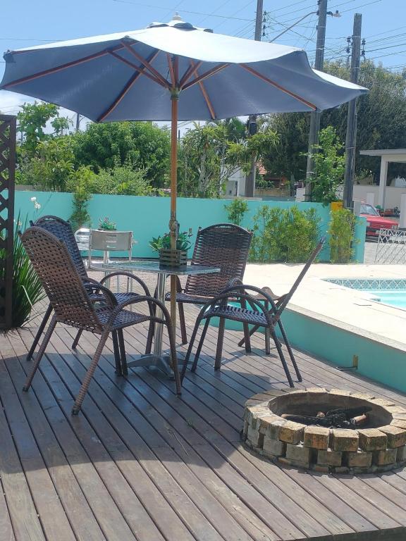 Duas cadeiras e uma mesa com um guarda-sol no deque em 01 - Casa Praia da Pinheira pousada em Palhoça