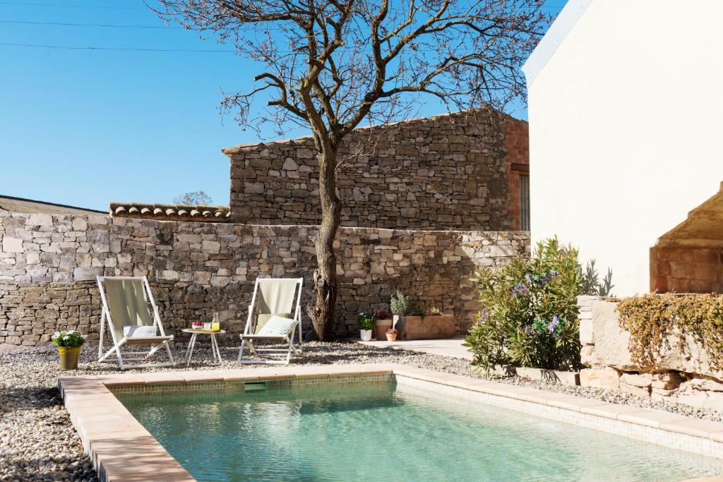 una piscina con due sedie, un tavolo e un muro di Casa Les Germanes a Gramuntell