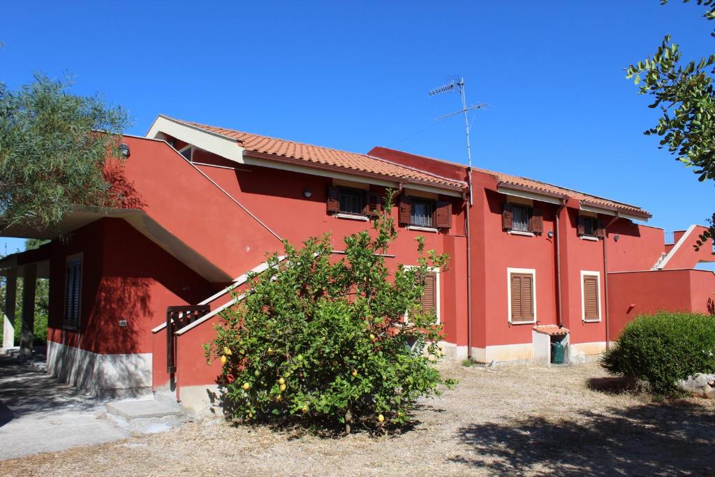 een rood gebouw met een boom ervoor bij Olmedo Casa Vacanze in Olmedo