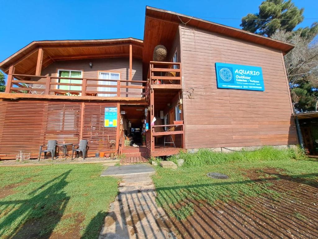 Cabaña de madera con balcón y sillas frente a ella en Cabañas Hostel Aquario Papudo en Papudo