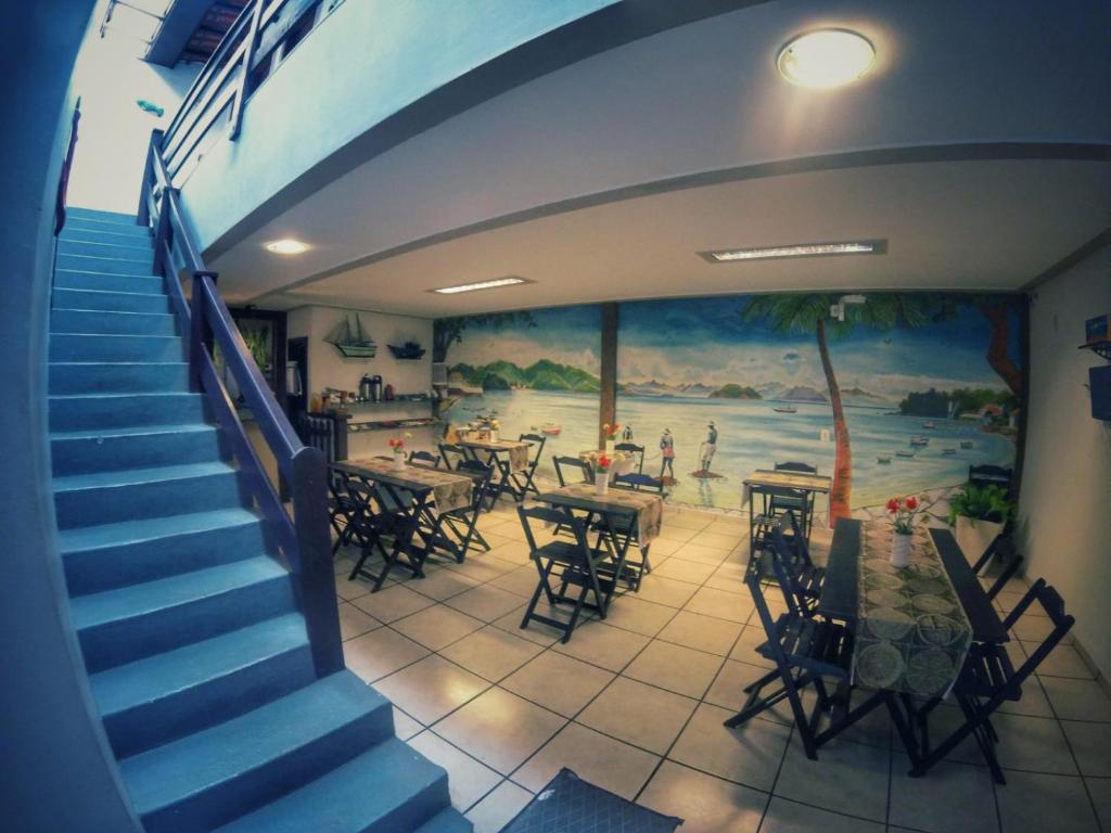 uma escadaria com um mural num restaurante com mesas e cadeiras em Pousada do Marinho em Búzios
