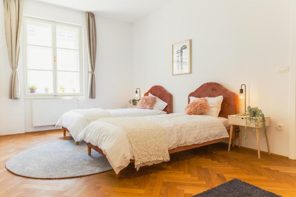 2 camas en un dormitorio con suelo de madera y ventana en Top location CITY CENTRE CONDO in historic building with free garage PARKING, en Liubliana