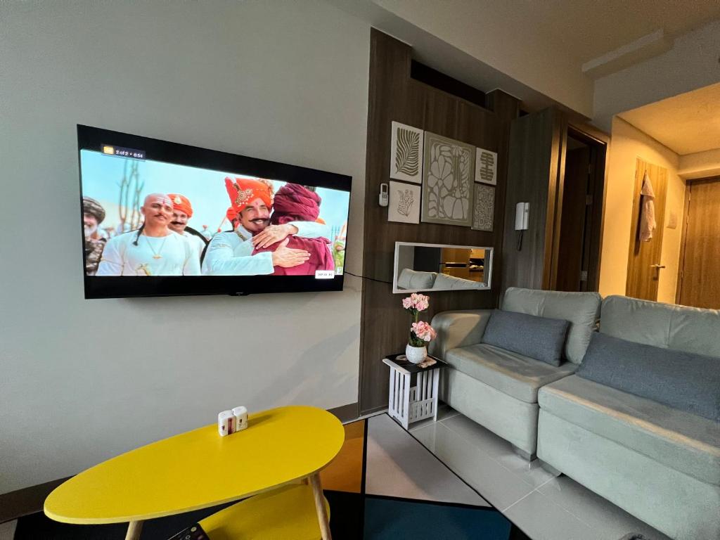 マニラにあるBeautiful 1bed condo Nr Airport, MOA, Makati, Bayのソファと壁掛けテレビのあるリビングルーム