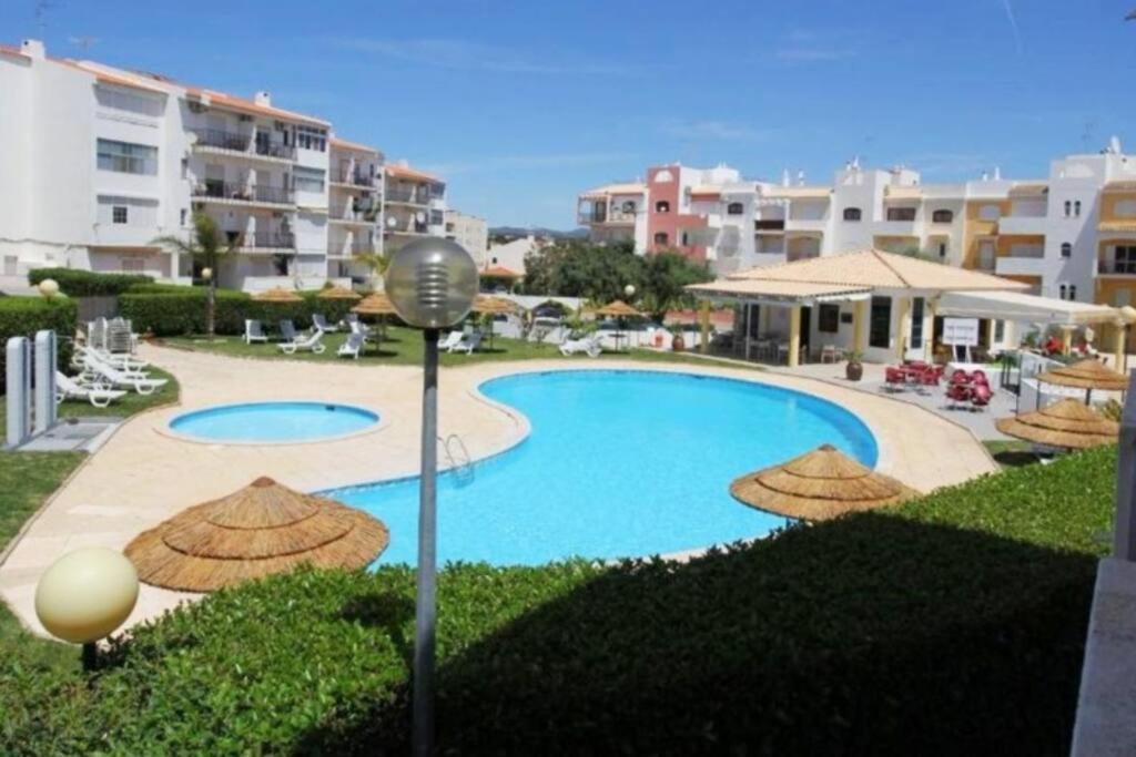 タヴィラにあるTavira Nature Houseのパラソル付きのスイミングプール、一部の建物