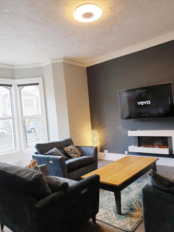 a living room with couches and a tv on a wall at No 27 Chapel Street Guest House in Llandudno