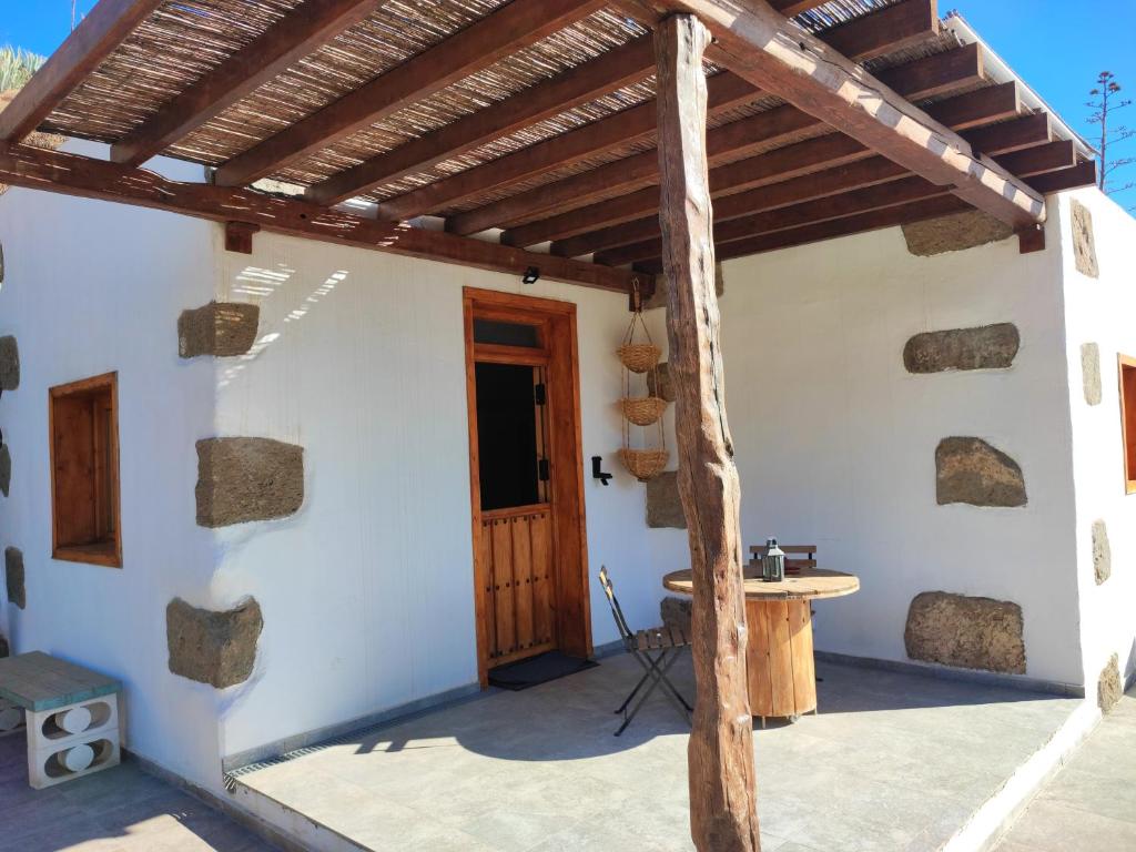 um pátio com uma pérgola de madeira e uma mesa em CASA DEL MAQUINISTA em Aguatona